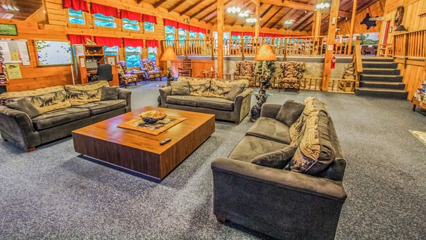A spacious lobby with multiple seating areas, wooden walls, and a high ceiling.