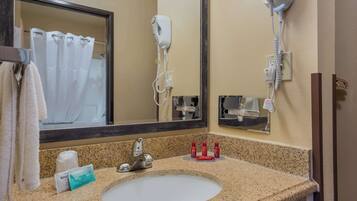 Een badkamer met een wastafel, spiegel, haardroger en toiletartikelen.