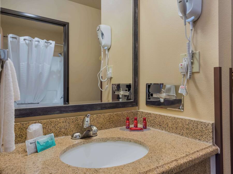 Een badkamer met een wastafel, spiegel, haardroger en toiletartikelen.