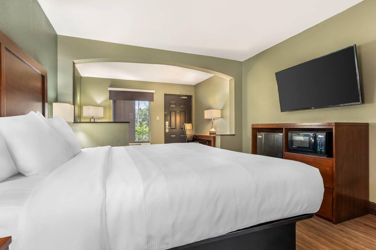 Habitación de hotel con una cama grande, un televisor de pantalla plana, un microondas y una puerta que da a un baño.