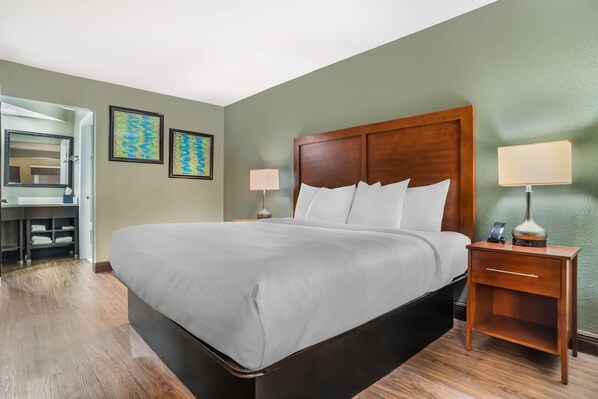 A hotel room with a large bed, bedside tables, a desk, and a mirror. - Quality Inn & Suites near Panama City Beach (Panama City)