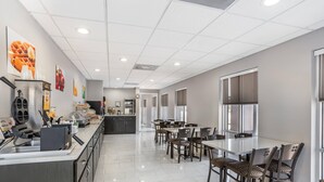 A clean, modern dining area with a buffet setup, including a refrigerator, food display, and seating arrangements. - Quality Inn & Suites near Panama City Beach (Panama City)