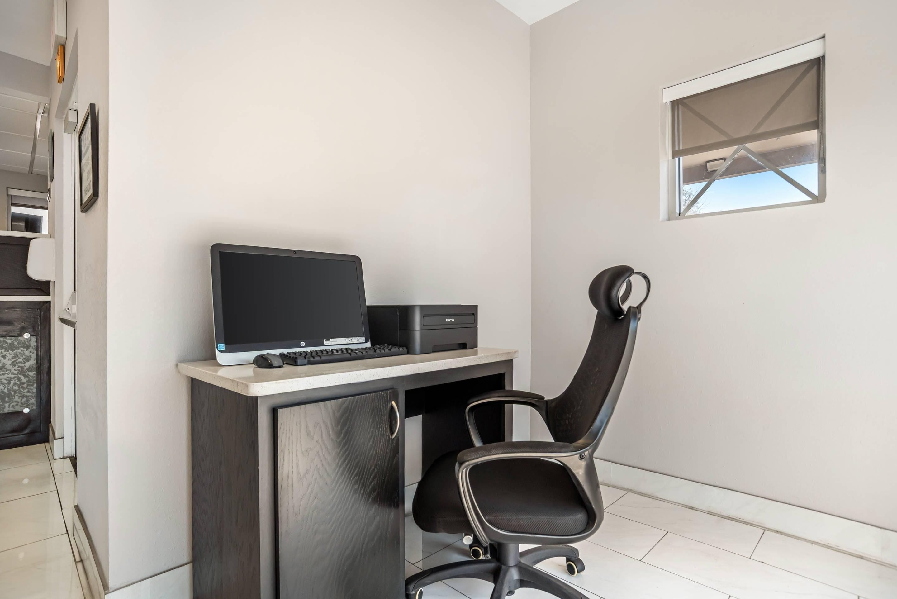 A small office space with a desk, chair, and a window.