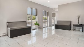 A spacious lobby with two dark-colored sofas, a small table with a vase, and a potted plant. - Quality Inn & Suites near Panama City Beach (Panama City)