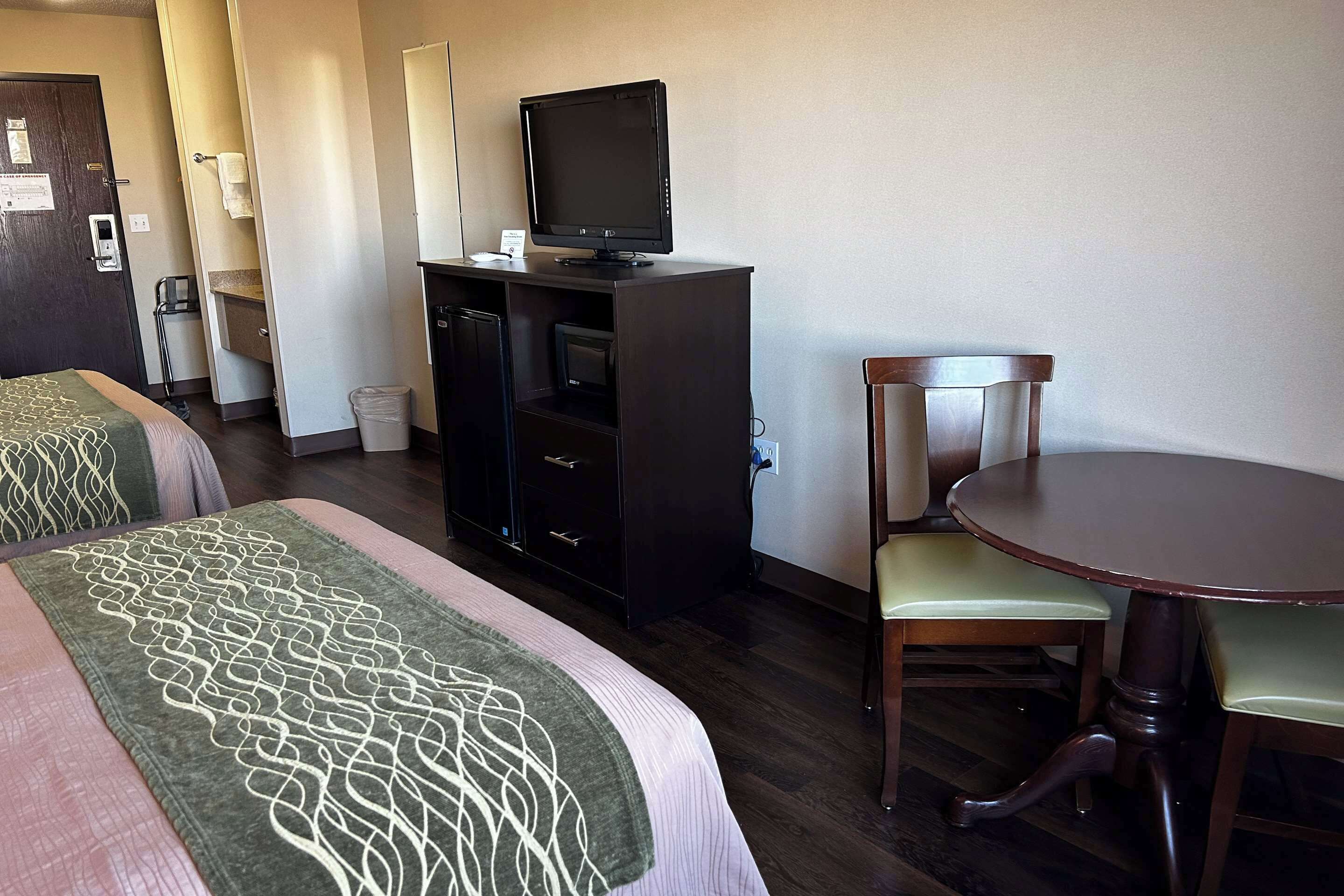 Une chambre d’hôtel avec deux lits, un bureau avec une télévision, une chaise et une petite table.