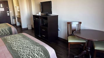 Une chambre d’hôtel avec deux lits, un bureau avec une télévision, une chaise et une petite table.