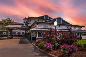 A Sedalia Station building with a covered walkway, outdoor seating, and flower planters.