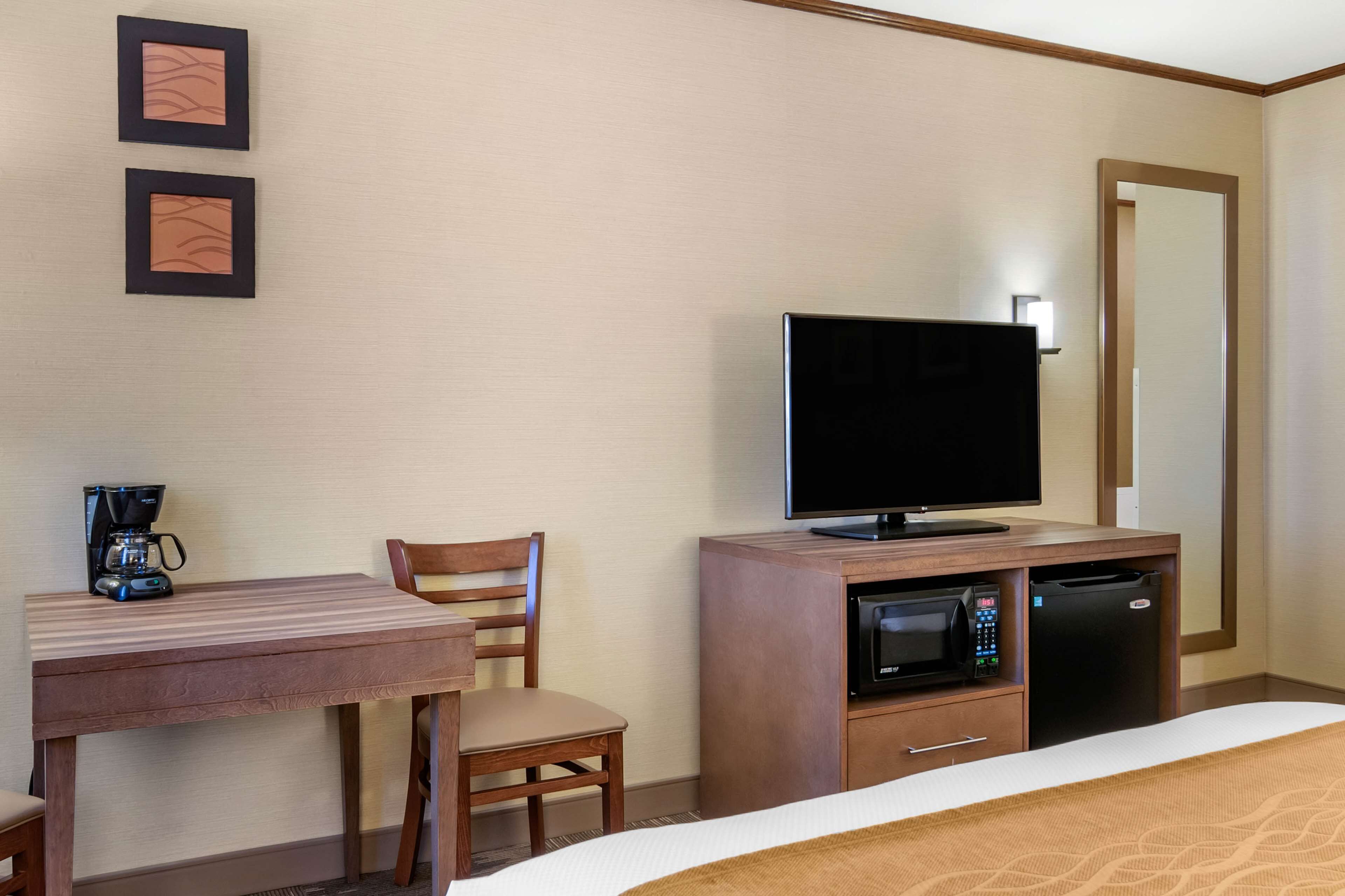 Una habitación de hotel con cama, televisión, cafetera, microondas y refrigerador.