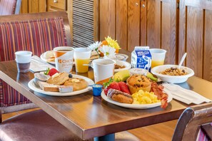 A breakfast table with various food items, including toast, muffins, and scrambled eggs, along with cups of coffee and juice.