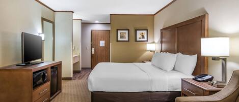 Una habitación de hotel con cama, televisión, escritorio, silla y lámpara.
