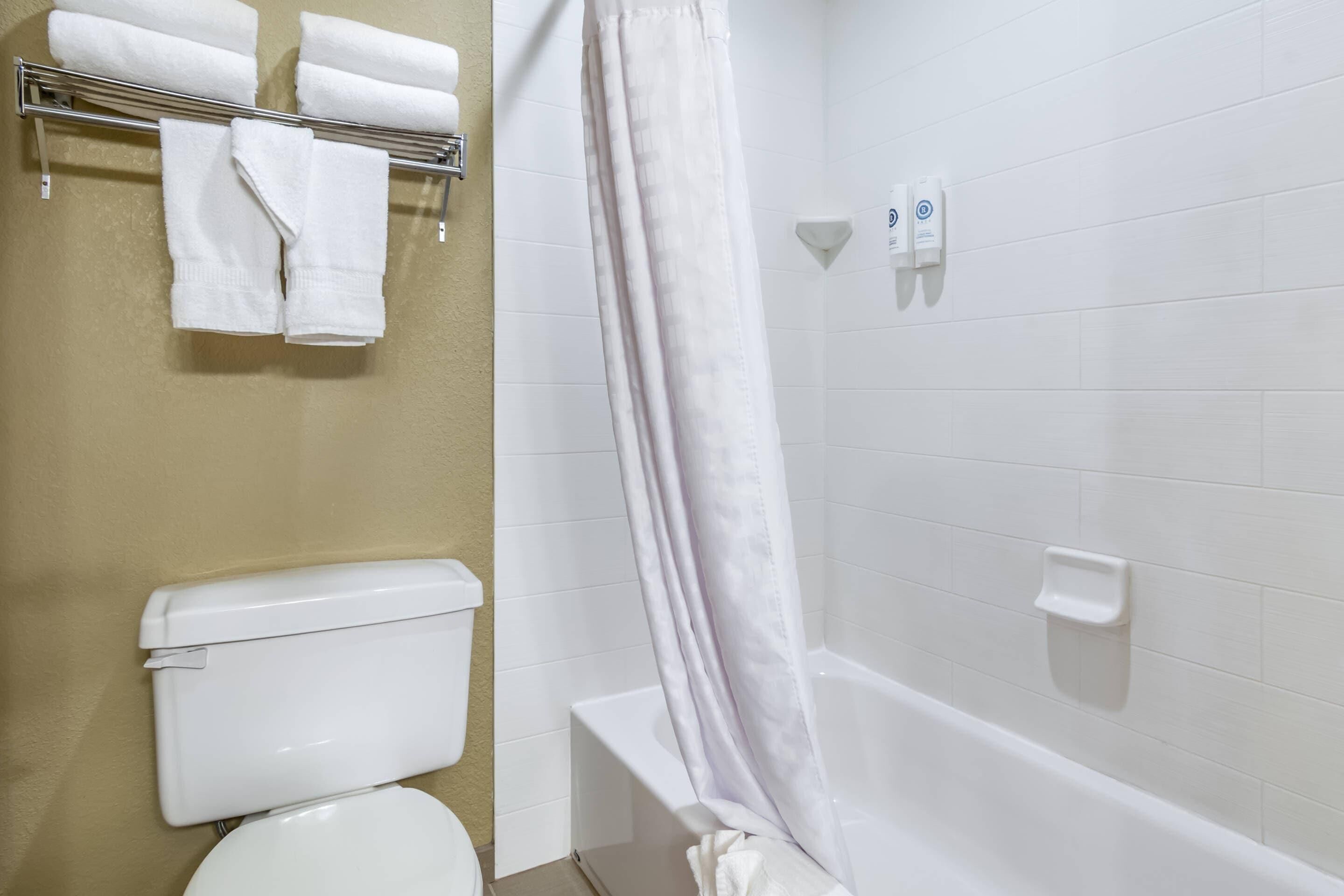 A bathroom with a toilet, a bathtub, and a towel rack with towels.