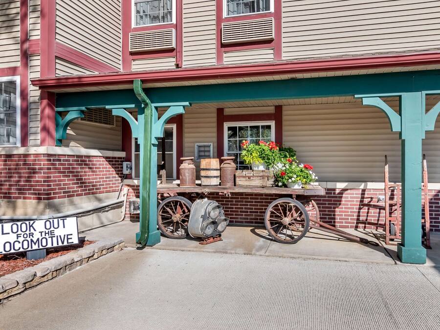 A building with a porch, a sign reading "LOOK OUT FOR THE LOCOMOTIVE", and vintage items displayed on the porch.