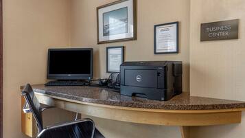 A business center desk with a Dell computer, a printer, and framed certificates on the wall.