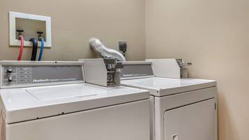 A commercial washer with control panel and hoses.