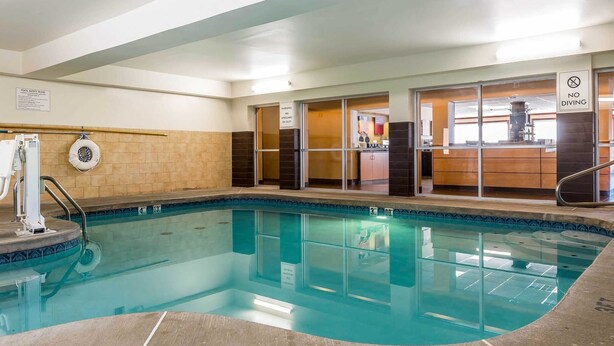 An indoor swimming pool with a safety sign, a lifeguard chair, and a no diving sign. - Comfort Suites Mason near Kings Island (Mason)