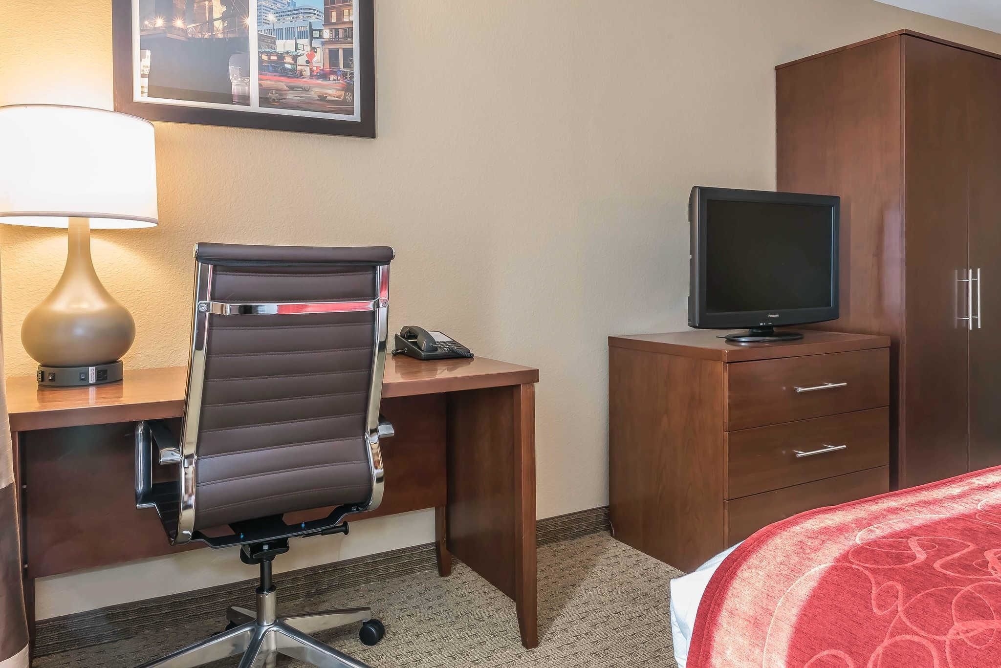 Habitación de hotel con escritorio, silla, lámpara, televisión y armario.