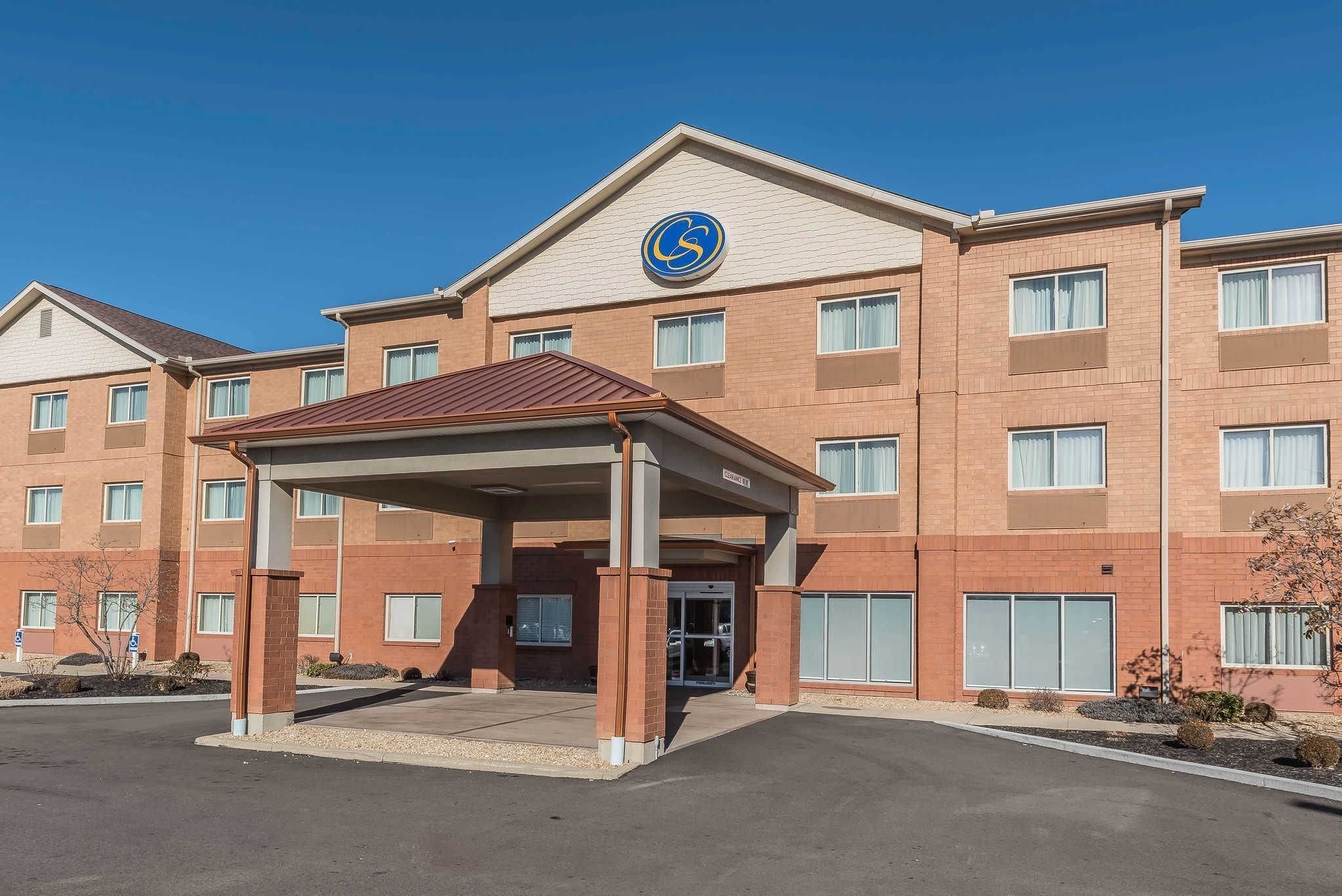 A multi-story hotel with a covered entrance and a prominent logo on the facade.