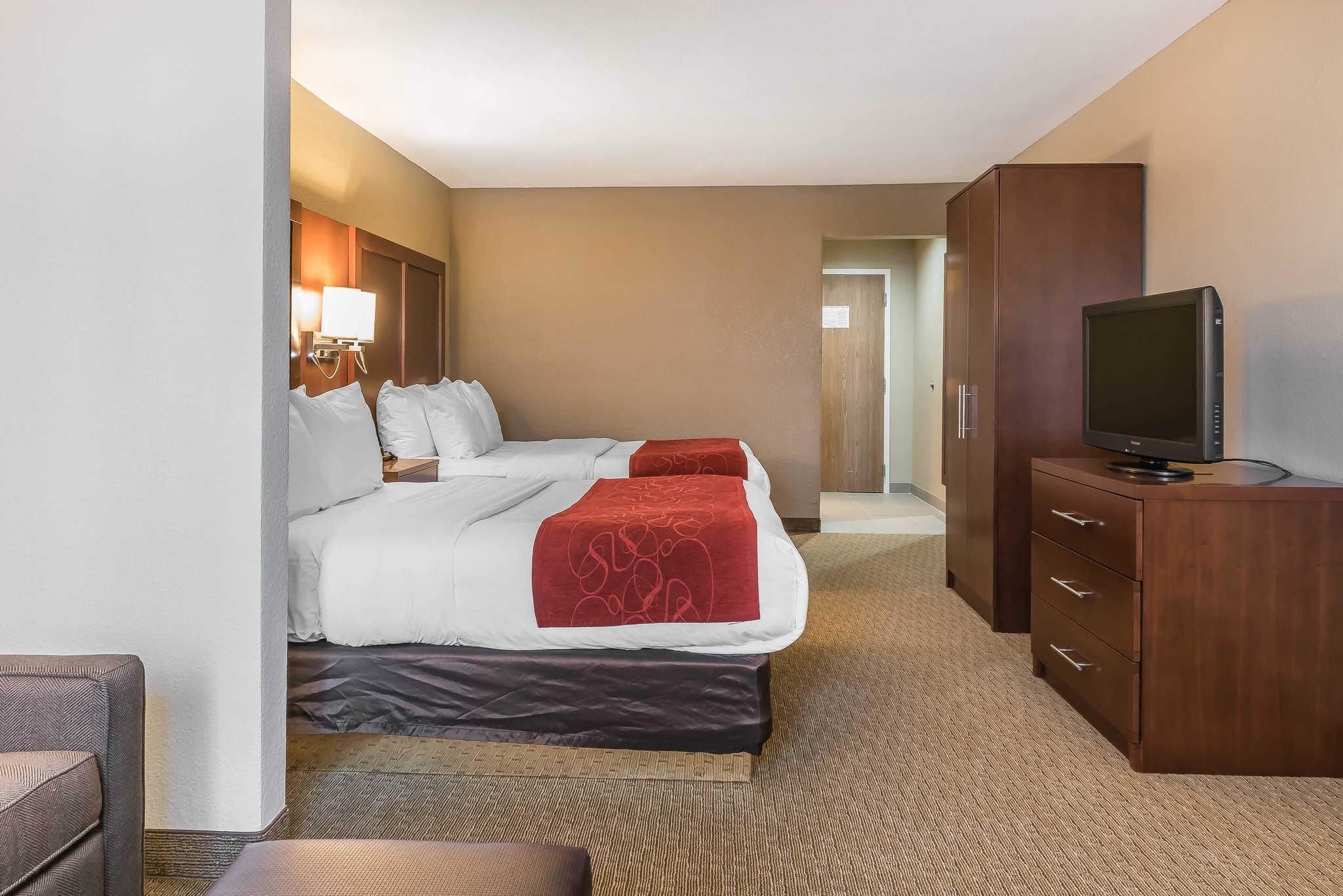 A hotel room with a bed, a TV, a desk, and a lamp.