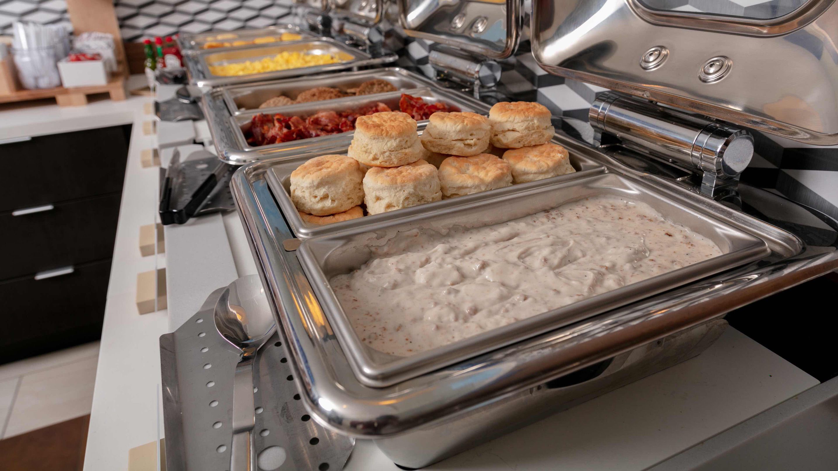 Een buffetopstelling met diverse gerechten, waaronder koekjes, roerei en een romige schotel.