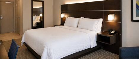 A hotel room with a large bed, bedside tables with lamps, a desk, and a chair.