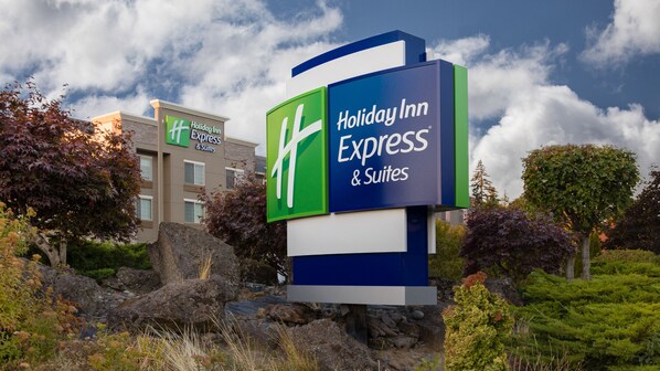 Welcome to the Holiday Inn Express & Suites, set amidst a beautifully landscaped area with lush trees and shrubs.