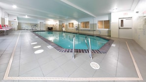 Une piscine intérieure avec des lignes de démarcation bien visibles pour les couloirs, un poste de surveillance pour le sauveteur et un escalier pour entrer dans la piscine.