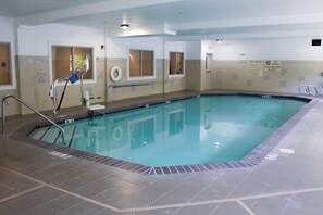 Swimmers can enjoy a rectangular pool surrounded by a tiled floor and decorative walls.