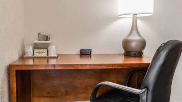 A hotel desk with a lamp, a chair, a non-smoking sign, and a power strip.