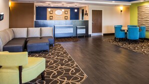 A hotel lobby with a reception desk, seating area, and a large blue wall.