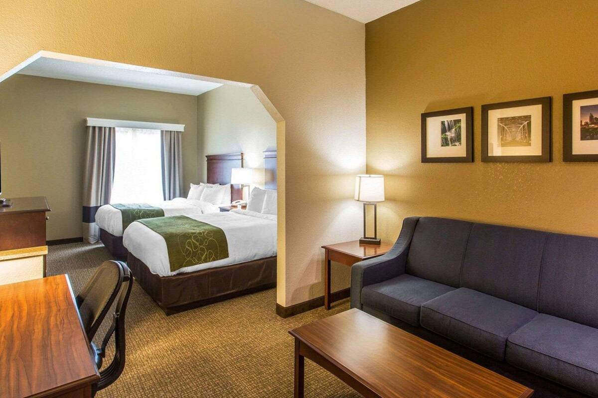 Une chambre d’hôtel avec deux lits, un canapé, un bureau et une lampe.