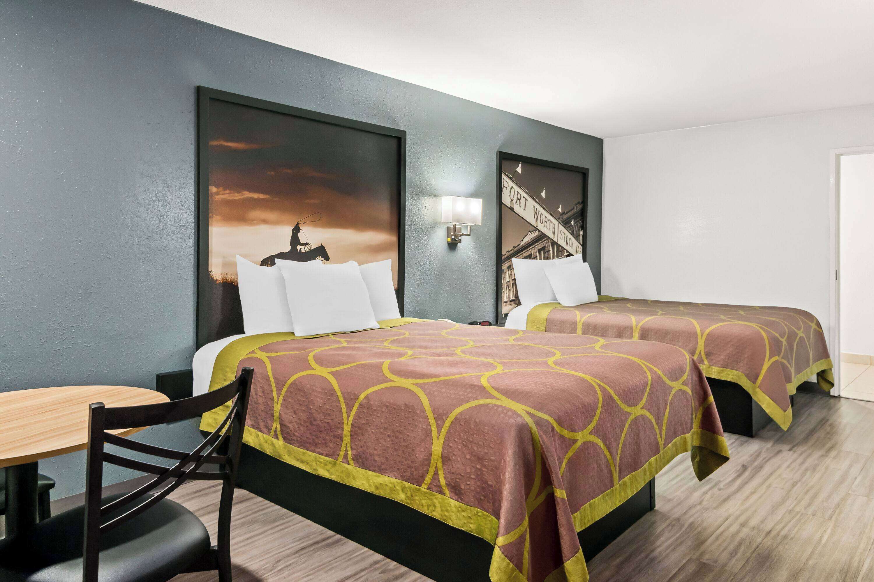 Ein Hotelzimmer mit zwei Betten, einem Schreibtisch und einem Stuhl.