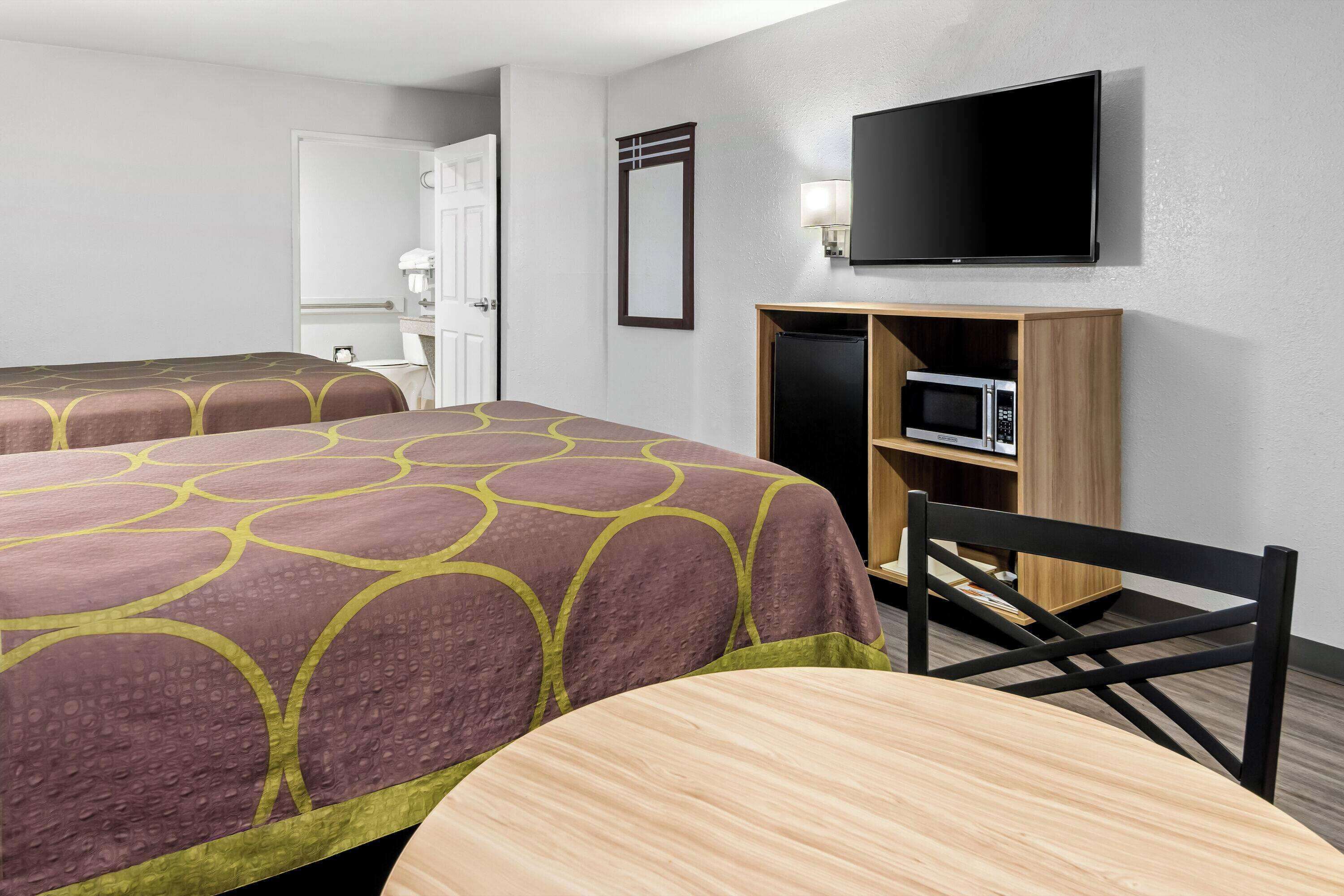 Une chambre d’hôtel avec deux lits, une télévision, un four à micro-ondes et un bureau avec une chaise.
