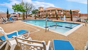 A swimming pool area with lounge chairs and a building in the background.