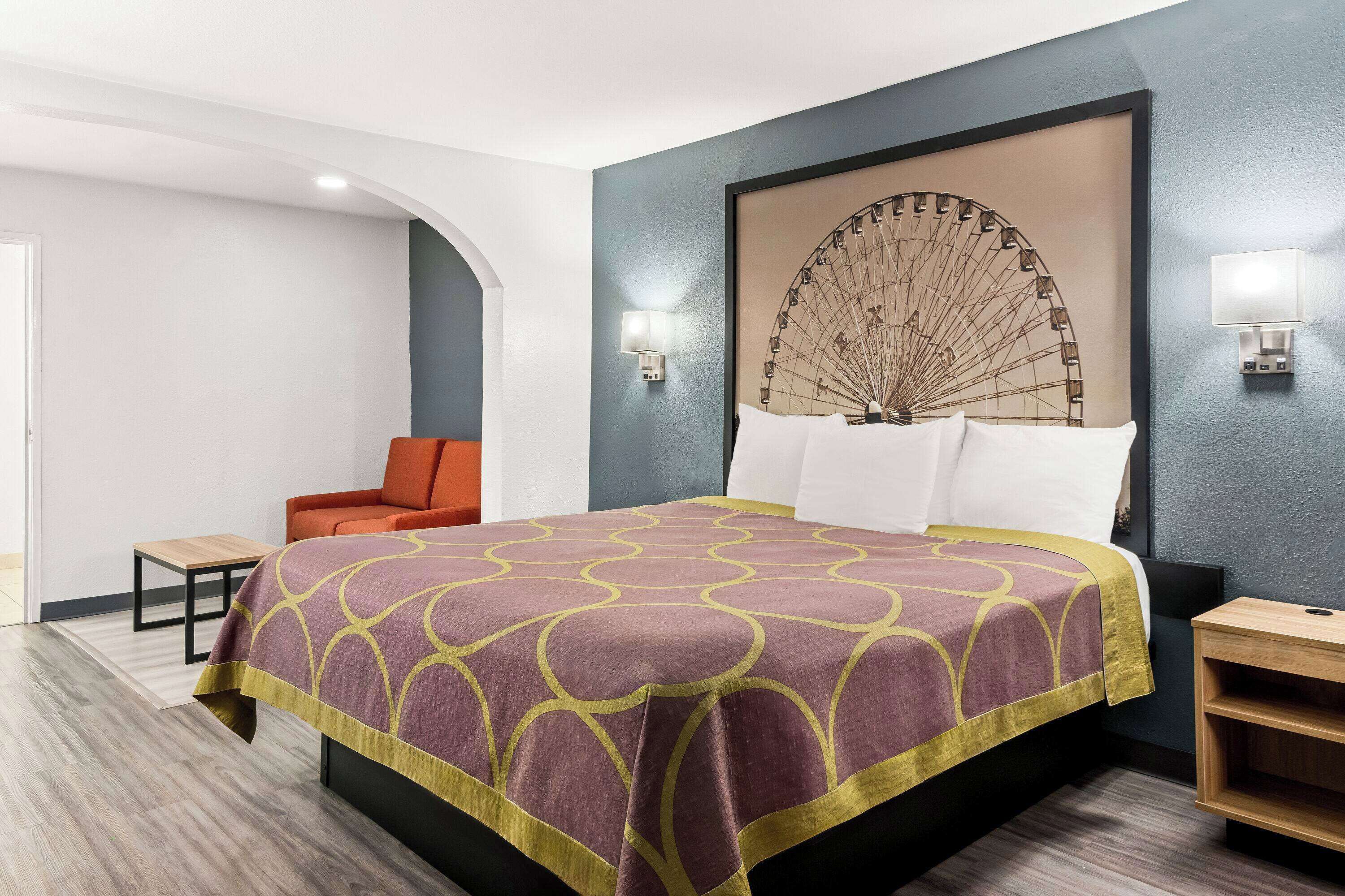 Una habitación de hotel con una cama, una silla, una mesita y una mesita de noche.