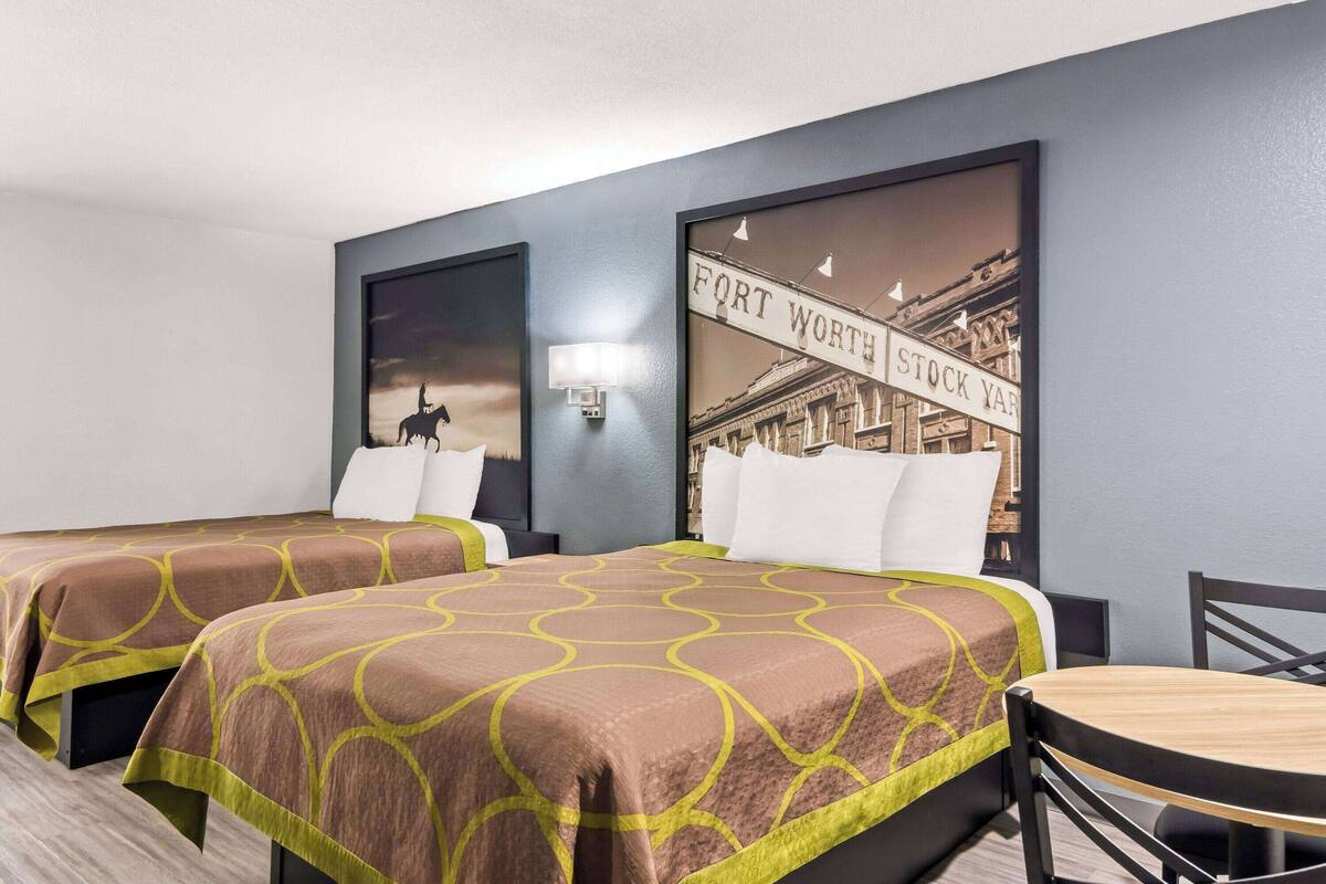 Een hotelkamer met twee bedden, een eettafel en een wandlamp.