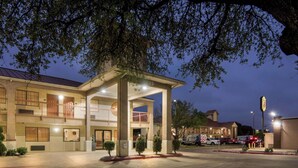 A hotel with a covered entrance, multiple floors, and a parking area with emergency vehicles.