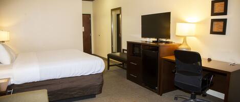 A hotel room with a bed, desk, chair, and television.