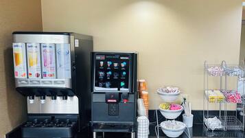 A coffee station with a Sunkist juice dispenser, a Nescafé coffee machine, and various coffee pods and utensils.