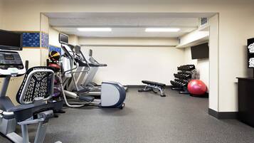 A gym with treadmills, stationary bikes, a rowing machine, dumbbells, and exercise balls.