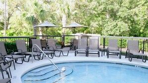 A poolside area with lounge chairs and umbrellas, surrounded by greenery. - Hampton Inn Amelia Island at Fernandina Beach (Fernandina Beach)