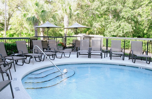 Una piscina al aire libre, sombrillas, sillones reclinables de piscina