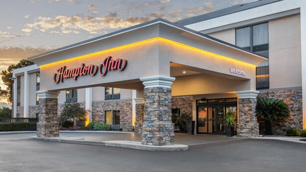 A Hampton Inn hotel with a stone facade, a 'Welcome' sign, and a well-lit entrance.