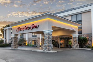 A Hampton Inn hotel with a stone facade, a 'Welcome' sign, and a well-lit entrance.
