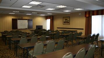 Un salón de conferencias con varias mesas y sillas, una pizarra y un cuadro en la pared.