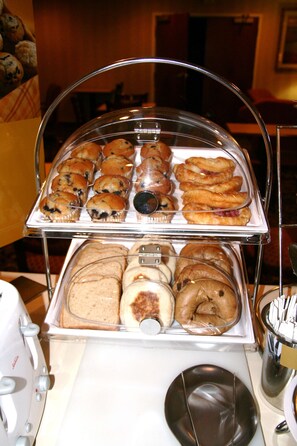 A buffet with various baked goods including muffins, pastries, and bread.