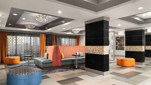 Eine moderne Hotelhalle mit Sitzgelegenheit, einer Rezeption und einer großen schwarzen Säule.