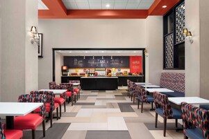 A modern restaurant with a central counter, booths, and tables.