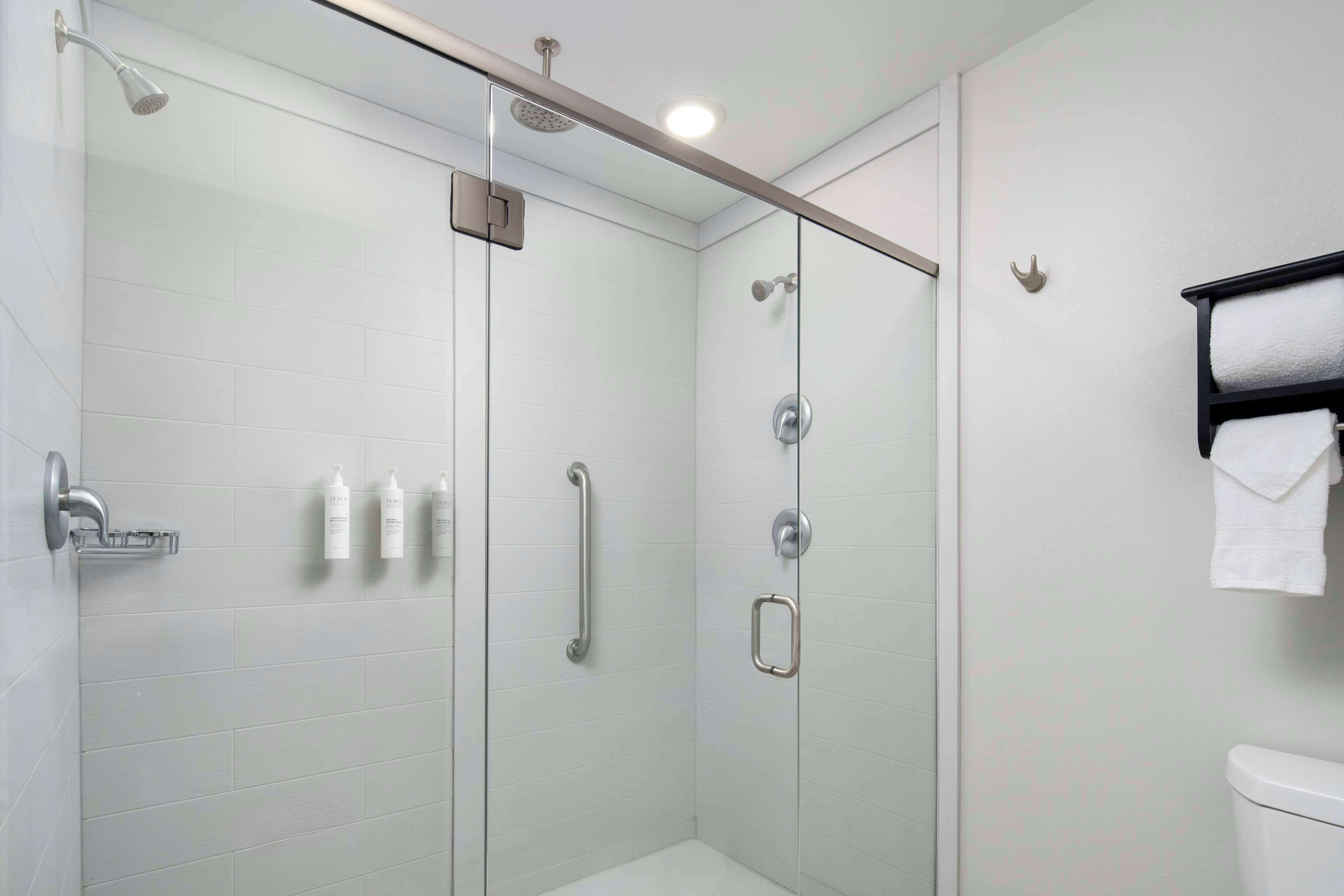A modern bathroom with a glass shower enclosure, a toilet, and a towel rack.