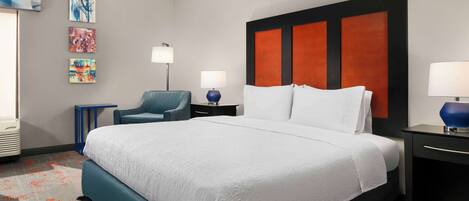 Una habitación de hotel con una cama grande, una silla, un escritorio y una lámpara.