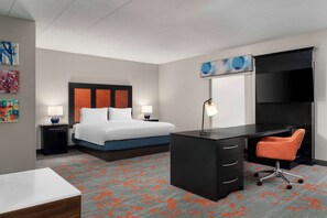 A hotel room with a bed, desk, chair, and a TV on a stand.